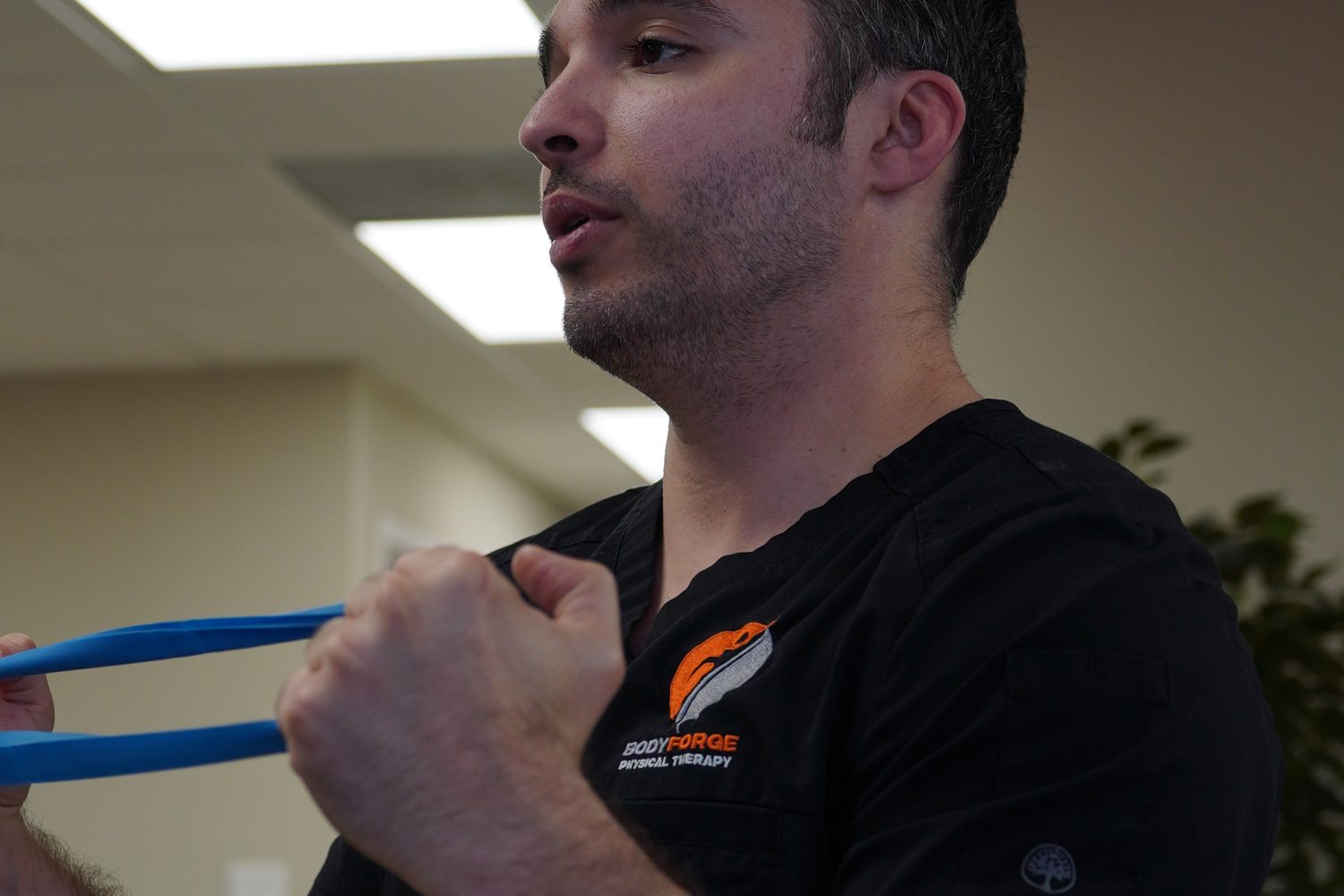 A clinician demonstrating a banded row, elbows tucked, before handing the band over.