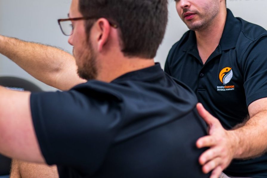 A hand placed flat on the back to cue breath and alignment during a controlled movement.