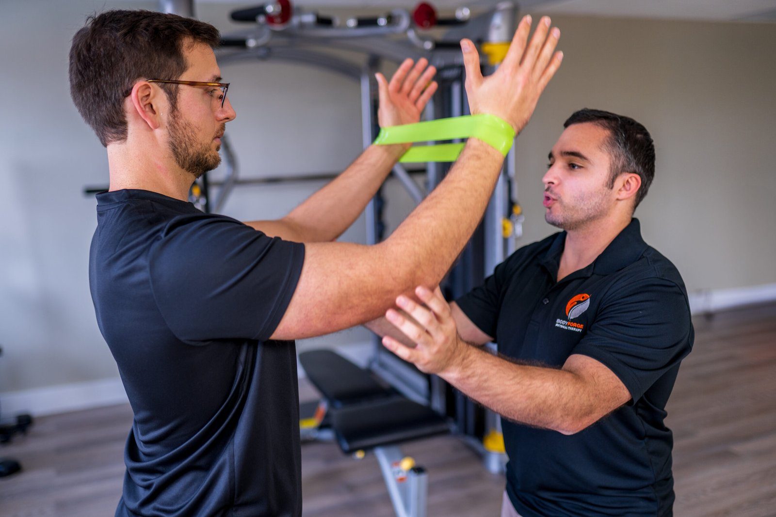 A hand placed on the shoulder blade to guide a patient through a banded exercise.