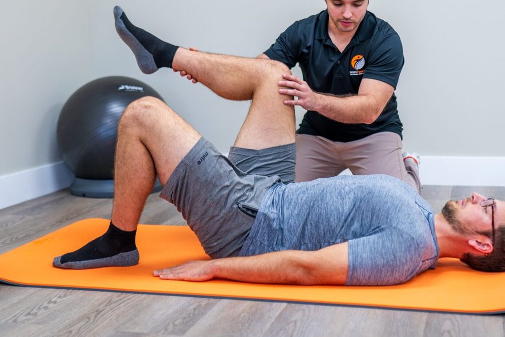 Hands-on knee and hip treatment on the mat at BodyForge.