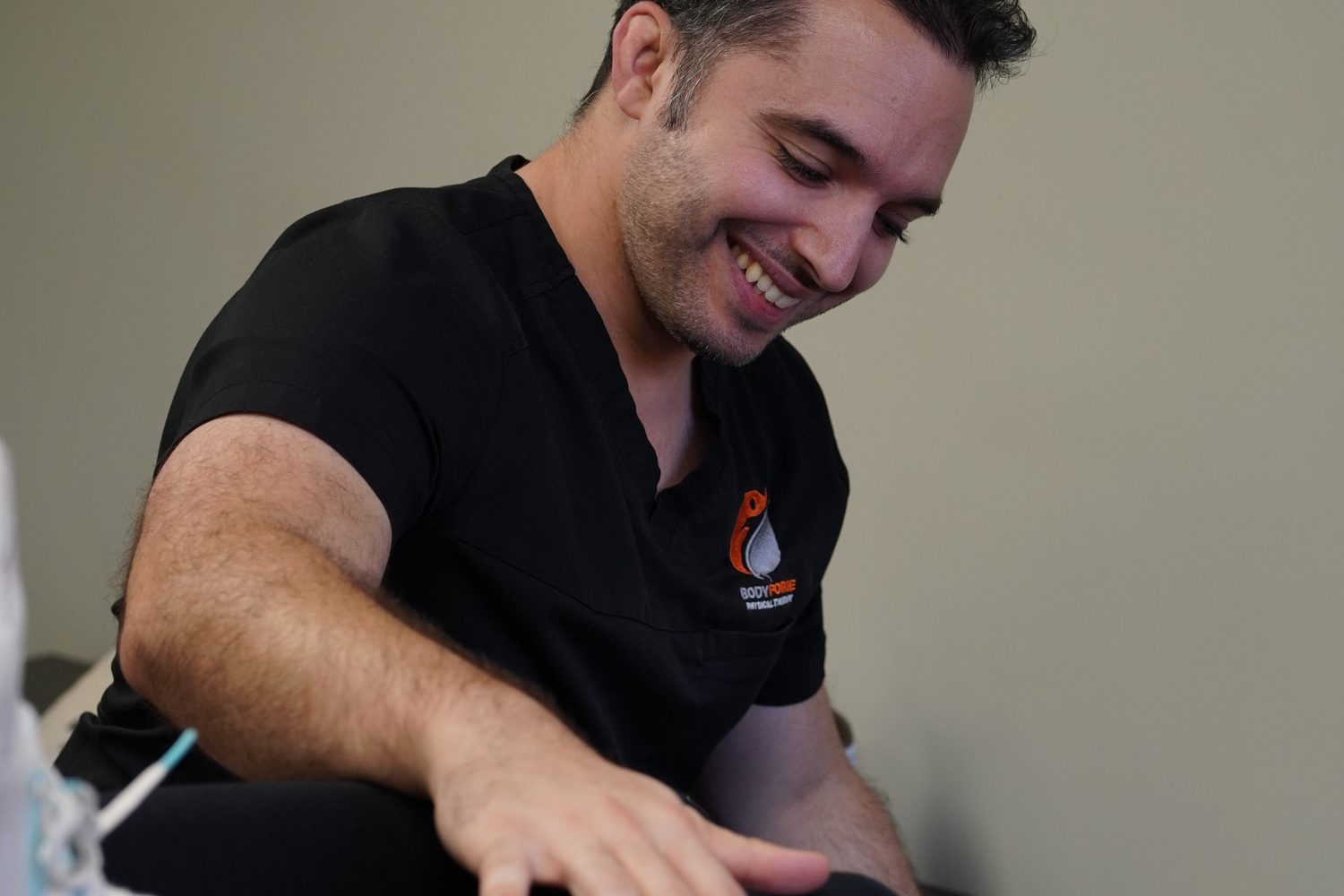 A BodyForge clinician working a patient's knee during a weekend recovery session.